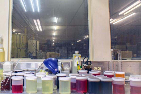 Small containers of solutions sit on a stainless steel table overlooking the plant at Dairy Dynamics